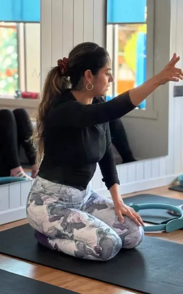 La instructora explica el ejercicio arrodillada sobre la colchoneta
